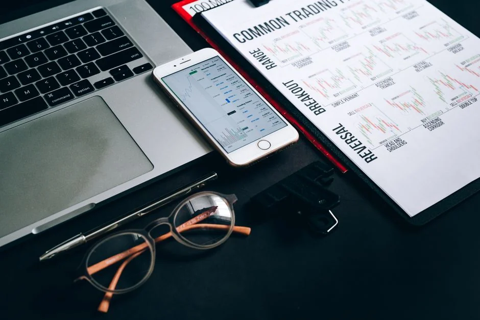 Une main tient un smartphone affichant le graphique BTC-USD au milieu d’écrans de trading numériques, mettant en avant la finance crypto.
